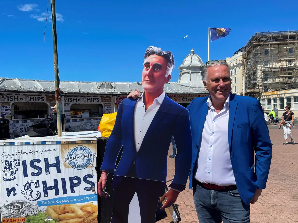 Steve Endacott, an independent candidate in the Brighton Pavilion race, poses with his AI avatar outside Brighton pier