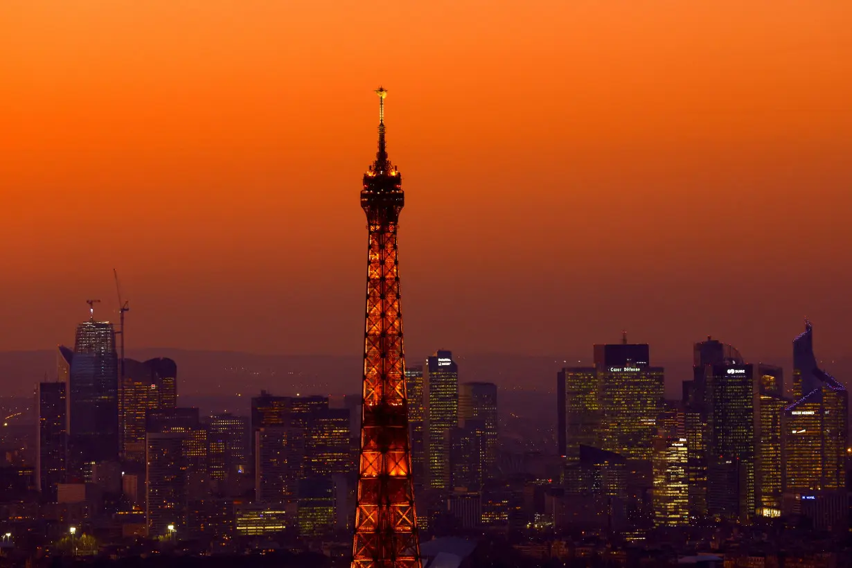 A view at sunset shows the Eiffel Tower and the financial and business district of La Defense in Puteaux near Paris