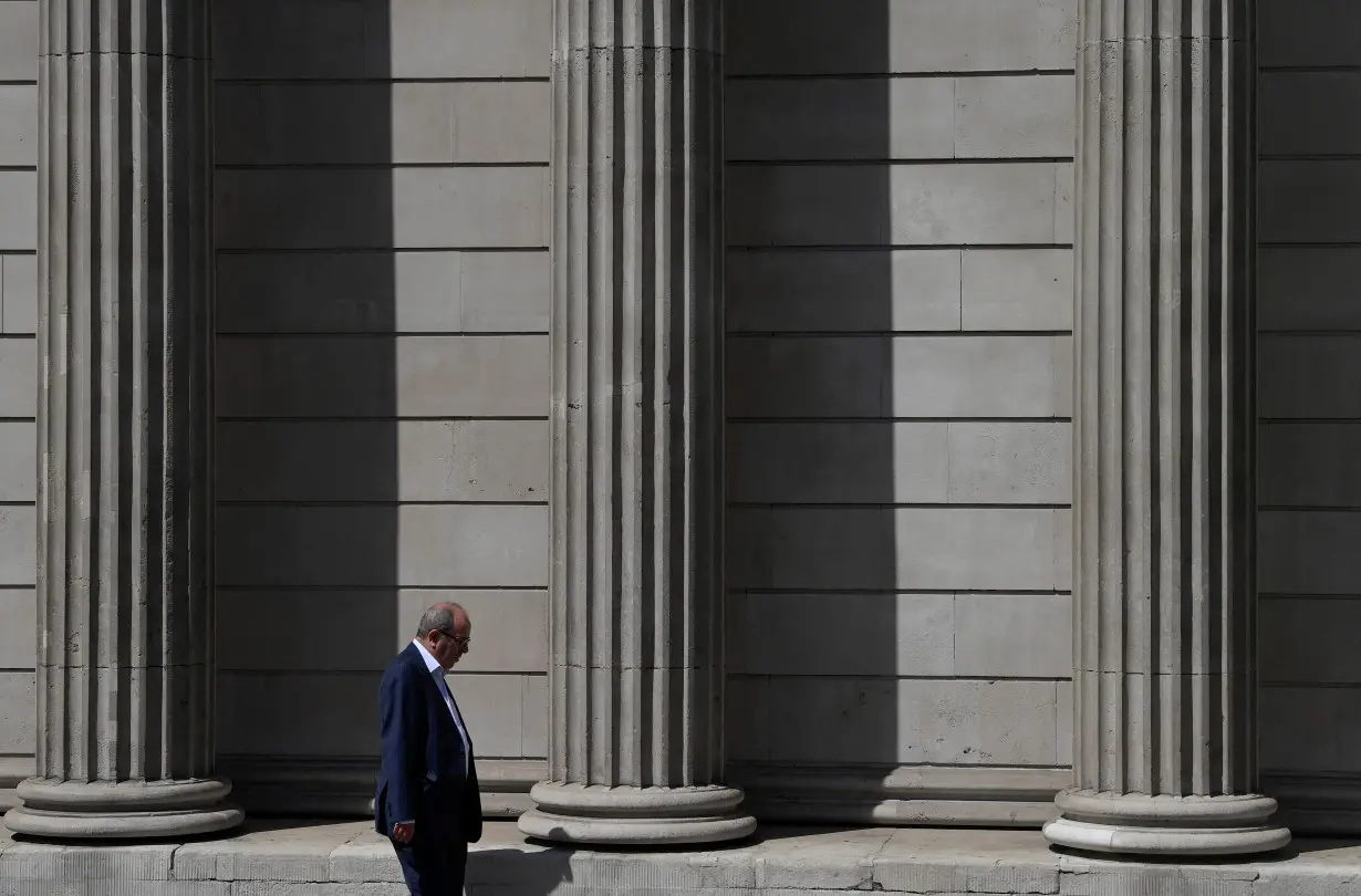 A worker walks past the Bank of England during the hot weather in the City of London financial district, London