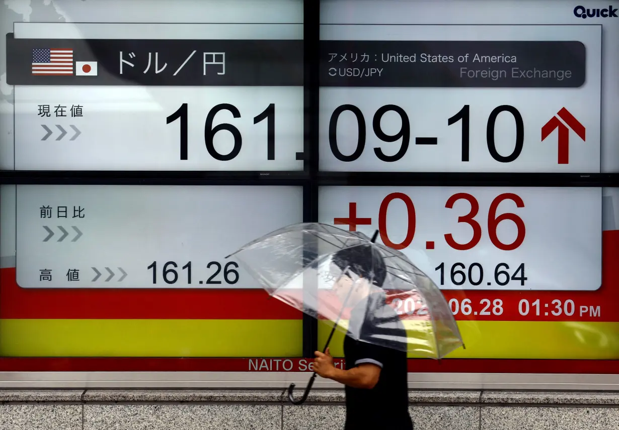 A person walks past an electric screen displaying the current Japanese Yen exchange rate against the U.S. dollar in Tokyo