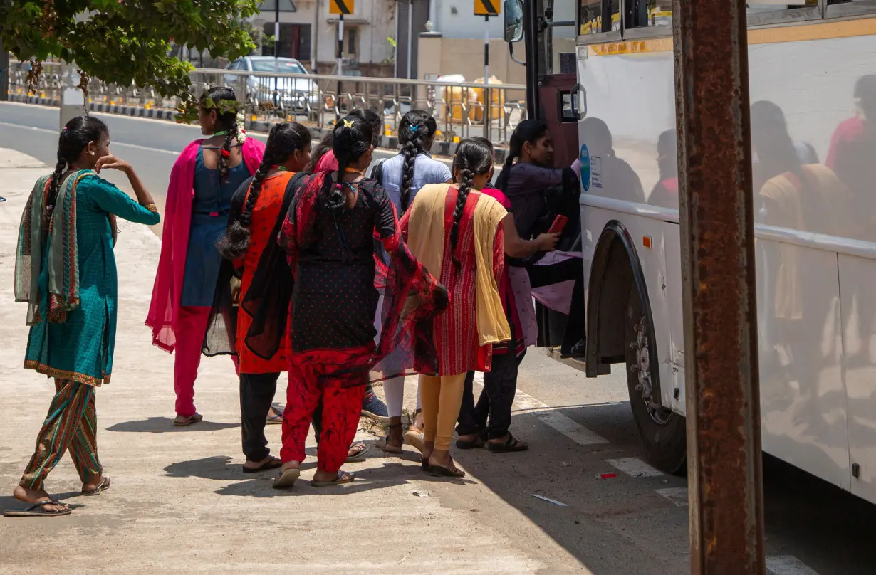 FILE PHOTO: Women board a Foxconn factory bus near the village of Molachur