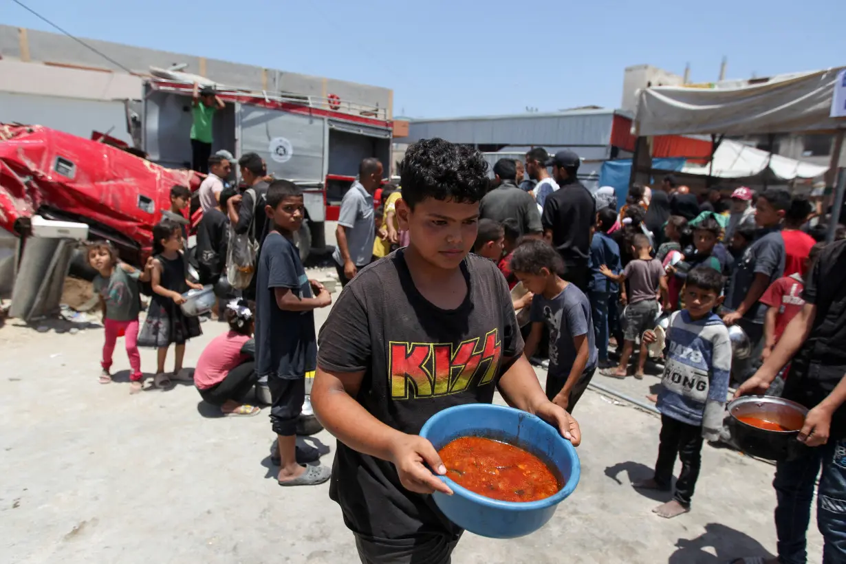 FILE PHOTO: Palestinians gather to receive food cooked by a charity kitchen, in Khan Younis