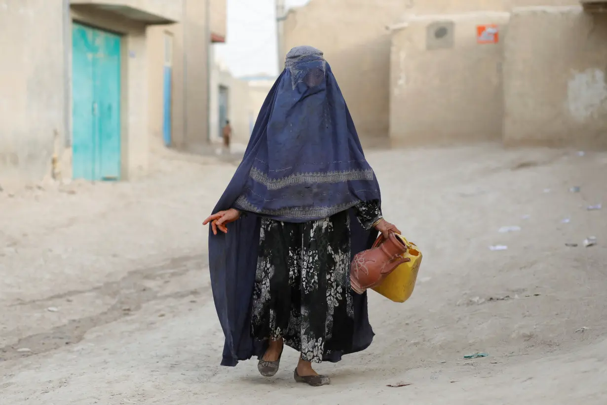 An Afghan woman carries empty containers to fetch water in Nahr-e-Shahi district in Balkh province