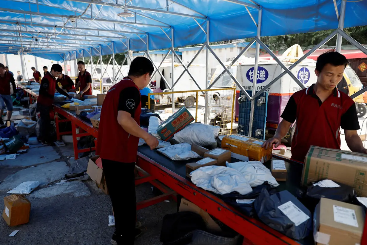 FILE PHOTO: Delivery workers sort packages on a conveyor belt, ahead of the 