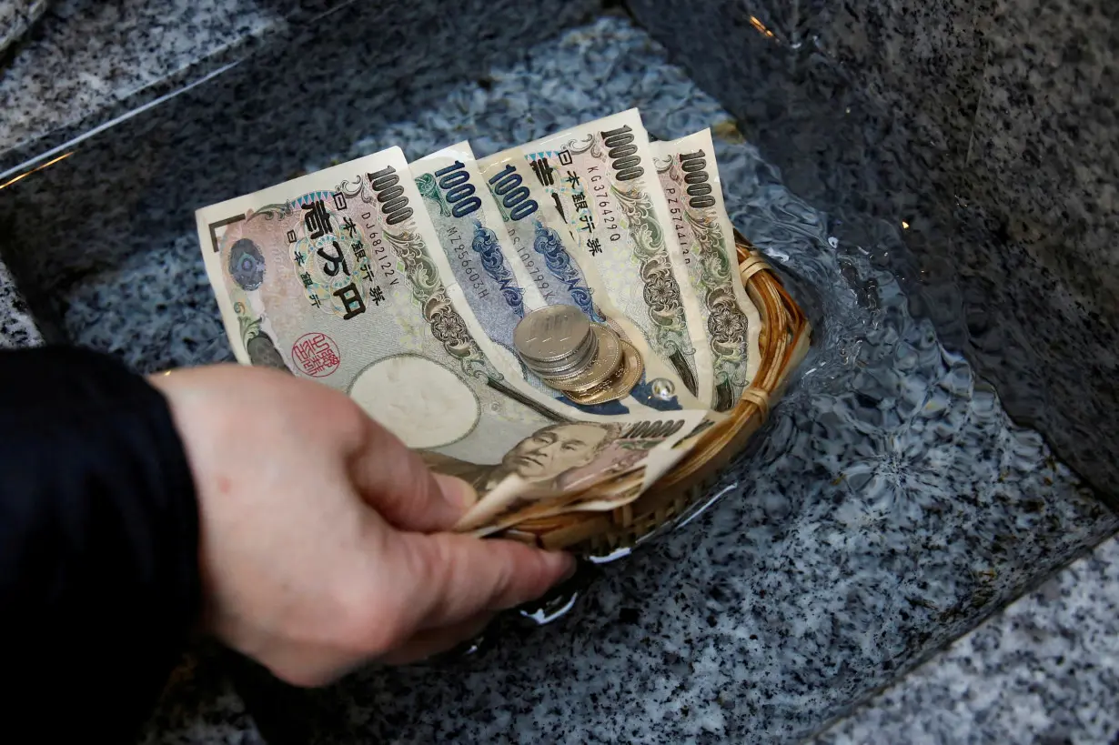 FILE PHOTO: Visitor washes Japanese yen banknotes and coins in water to pray for prosperity at Koami shrine in Tokyo's Nihonbashi business district