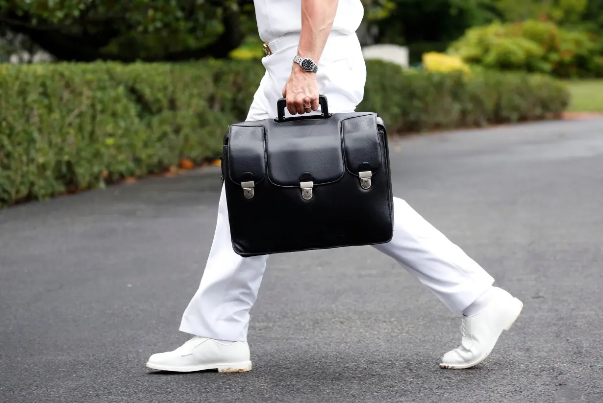 A military aide carries a briefcase containing launch codes for nuclear weapons as U.S. President Donald Trump returns to the White House in Washington