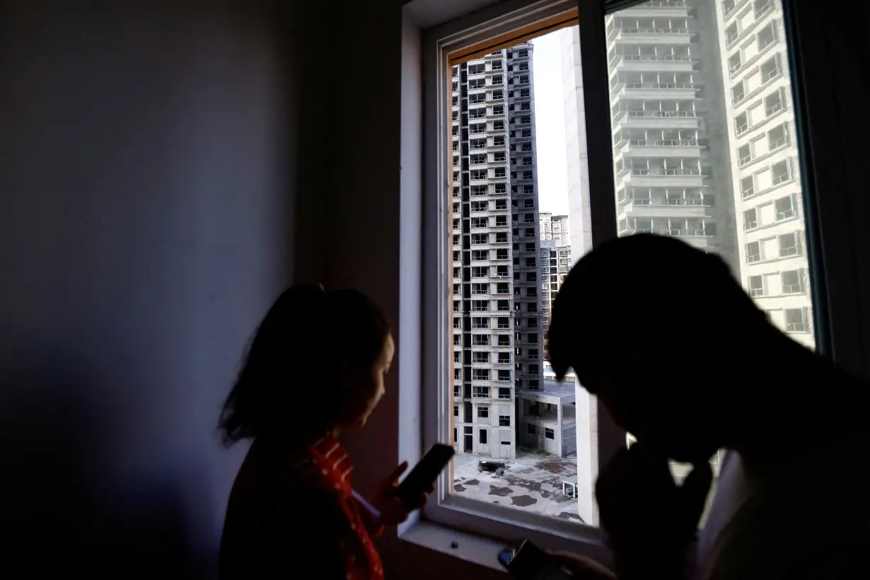 Home buyers stand near a window at an unfinished residential building in Tongchuan