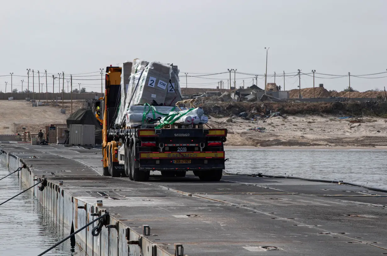 FILE PHOTO: Trucks deliver humanitarian aid over a temporary pier on the Gaza coast