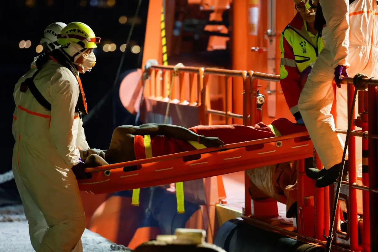 Rescuers disembark a migrant in critical condition from a Spanish coast guard vessel at the port of Arguineguin