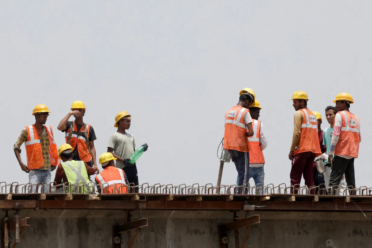 FILE PHOTO: Workers drink water as they take a break at a construction site on a hot summer day