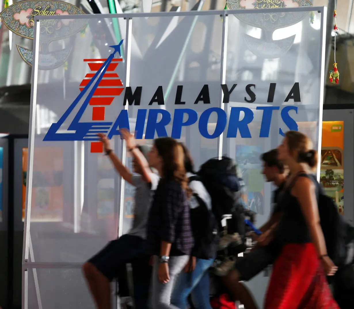 FILE PHOTO: Travellers push their trolley past a logo of Malaysia Airports at the departure hall of Kuala Lumpur International Airport in Sepang