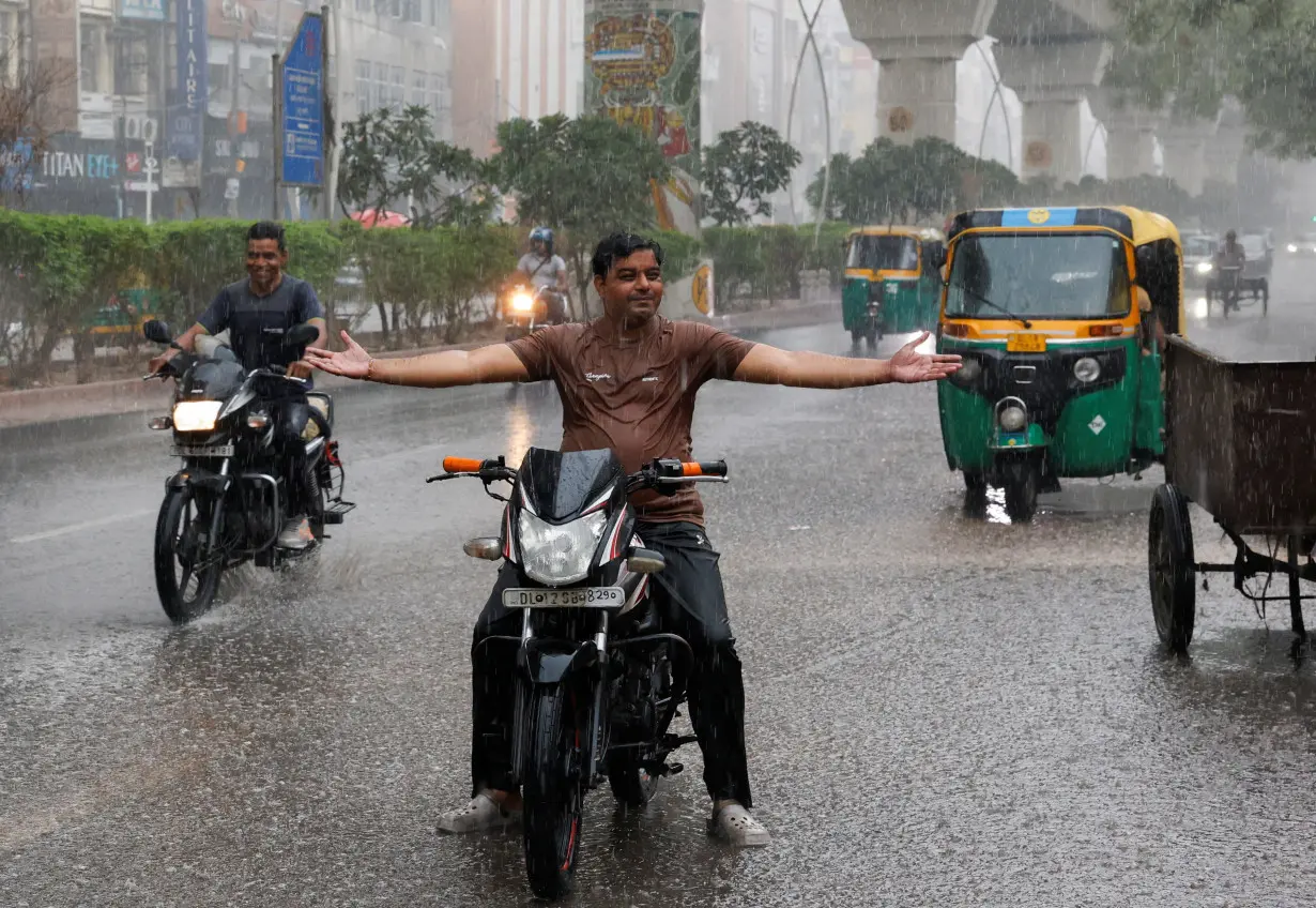 A man reacts during rainfall as the temperature dips in the capital upon the arrival of monsoon