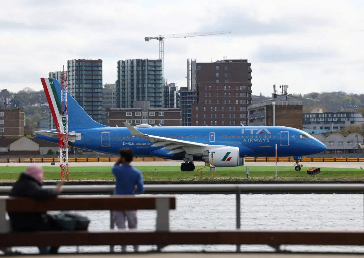 People watch as an ITA Airways Airbus A220-100 takes off from London City Airport
