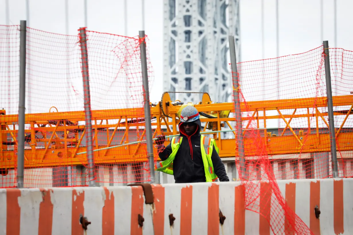 A construction worker carries a steel bar at the site of a large public infrastructure reconstruction project in New York