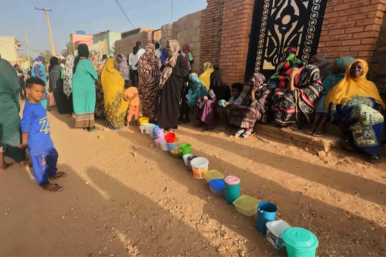 Residents collect food in containers in Omdurman