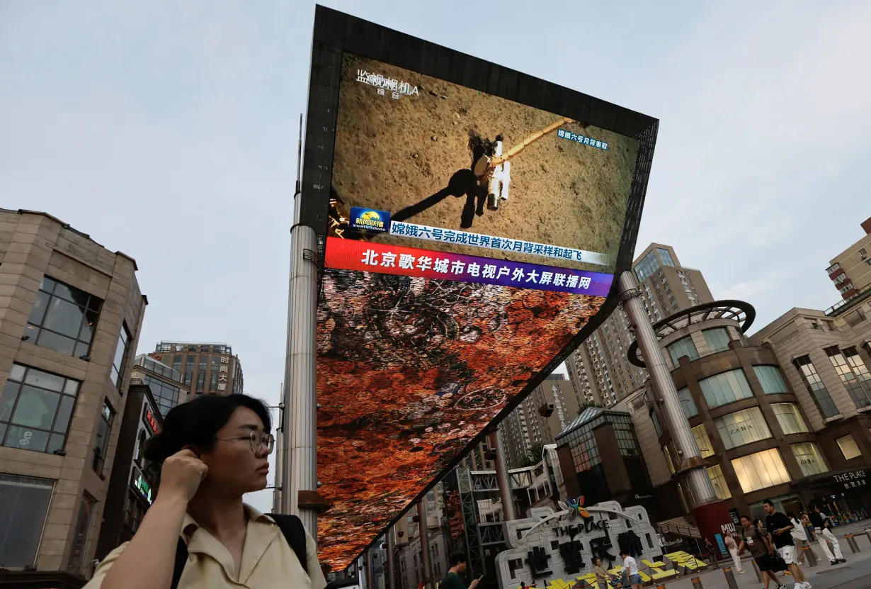 Screen shows news footage of China's Chang'e-6 lunar probe collecting sample from the far side of the moon, in Beijing