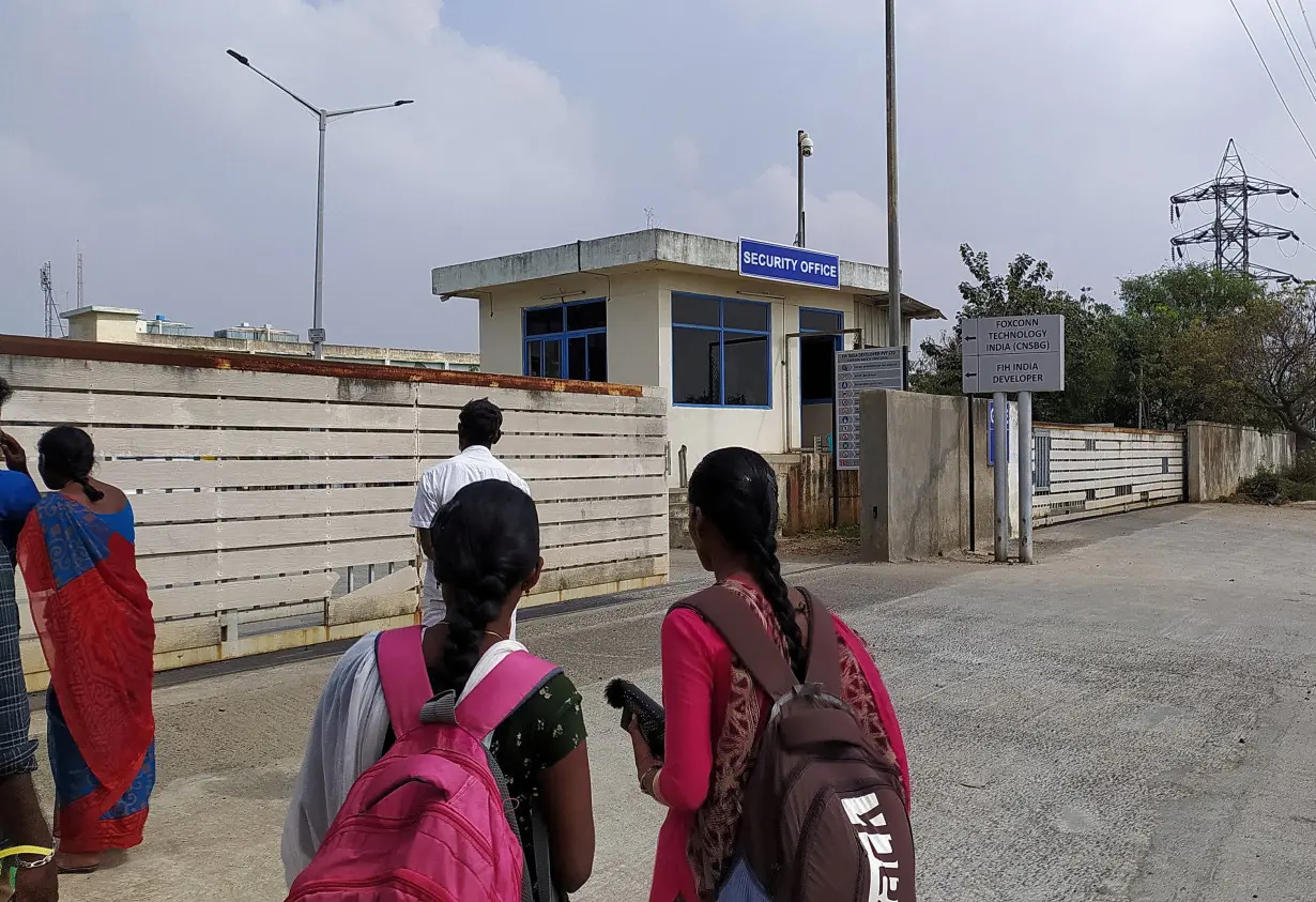 FILE PHOTO: Two women wearing backpacks stand outside a security office at the main entrance to Foxconn's factory in Sriperumbudur