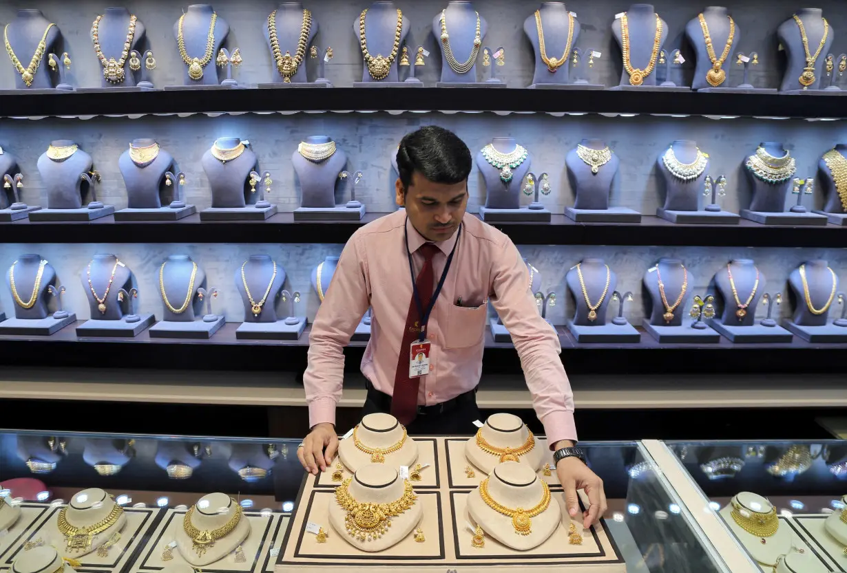 FILE PHOTO: A salesman displays gold necklaces and earrings inside a jewellery showroom on the occasion of Akshaya Tritiya, a major gold buying festival, in Mumbai