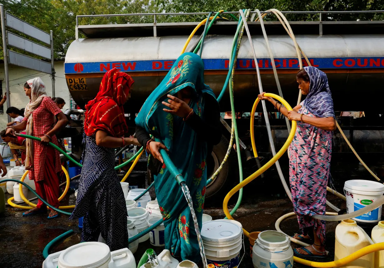 Residents use pipes to fill their containers with drinking water from a water tanker