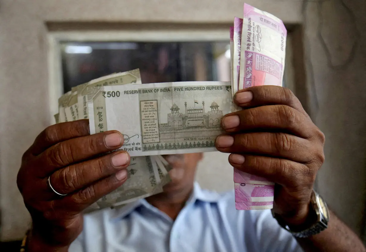 FILE PHOTO: FILE PHOTO: A cashier checks Indian rupee notes inside a room at a fuel station in Ahmedabad