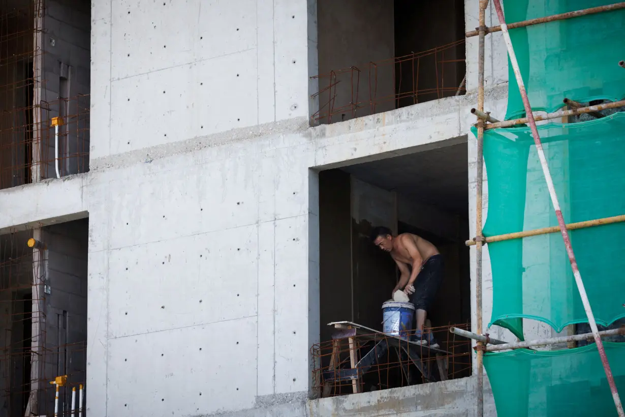 FILE PHOTO: A man works at a construction site of apartment buildings in Beijing