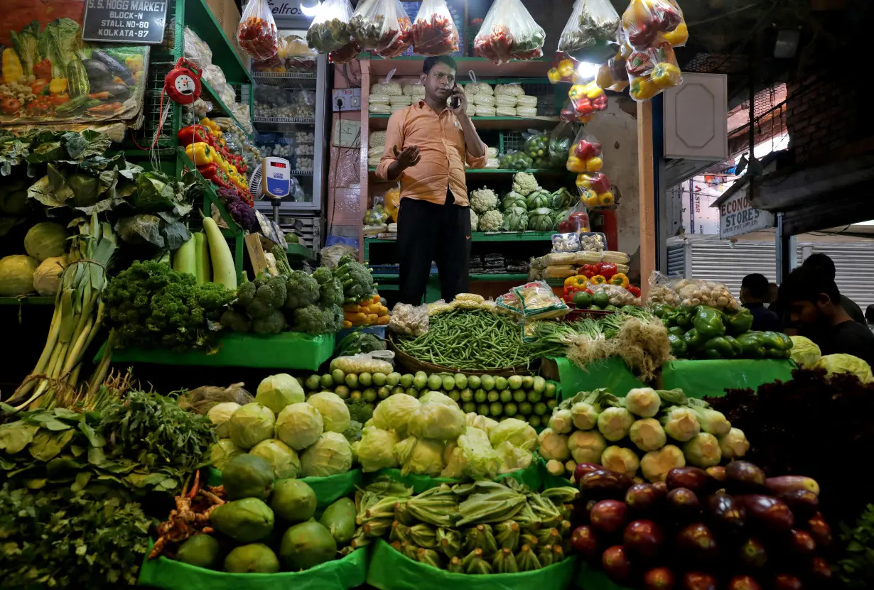 FILE PHOTO: Debashis Dhara, a vegetable vendor, speaks on his mobile phone at a retail market area in Kolkata