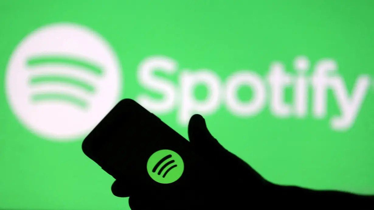 FILE PHOTO: A smartphone is seen in front of a screen projection of Spotify logo, in this picture illustration