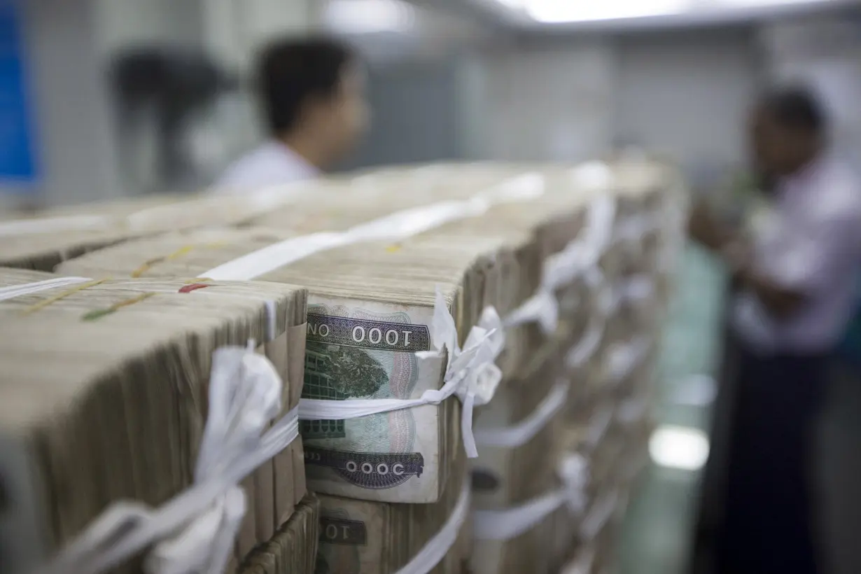 FILE PHOTO: Stacks of Myanmar kyat are seen on the counter before a client collects them, at a bank in Yangon, Myanmar