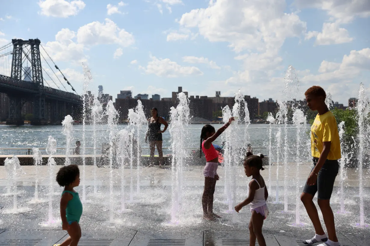 FILE PHOTO: People cool off in a water feature in Domino Park as a heat wave hit the region in Brooklyn, New York City