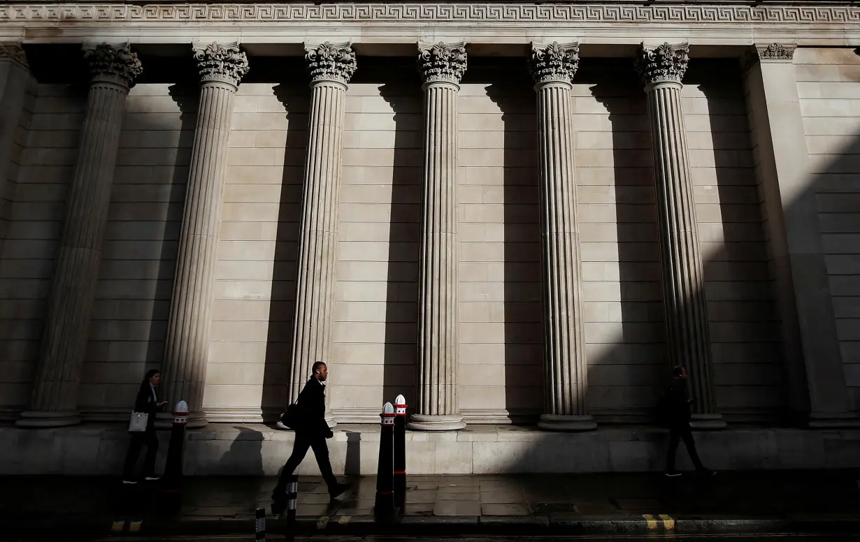 FILE PHOTO: A commuter walks past the Bank of England, in London