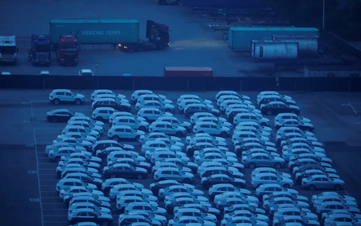 A truck transporting a shipping container drives past imported vehicles at Pyeongtaek port in Pyeongtaek