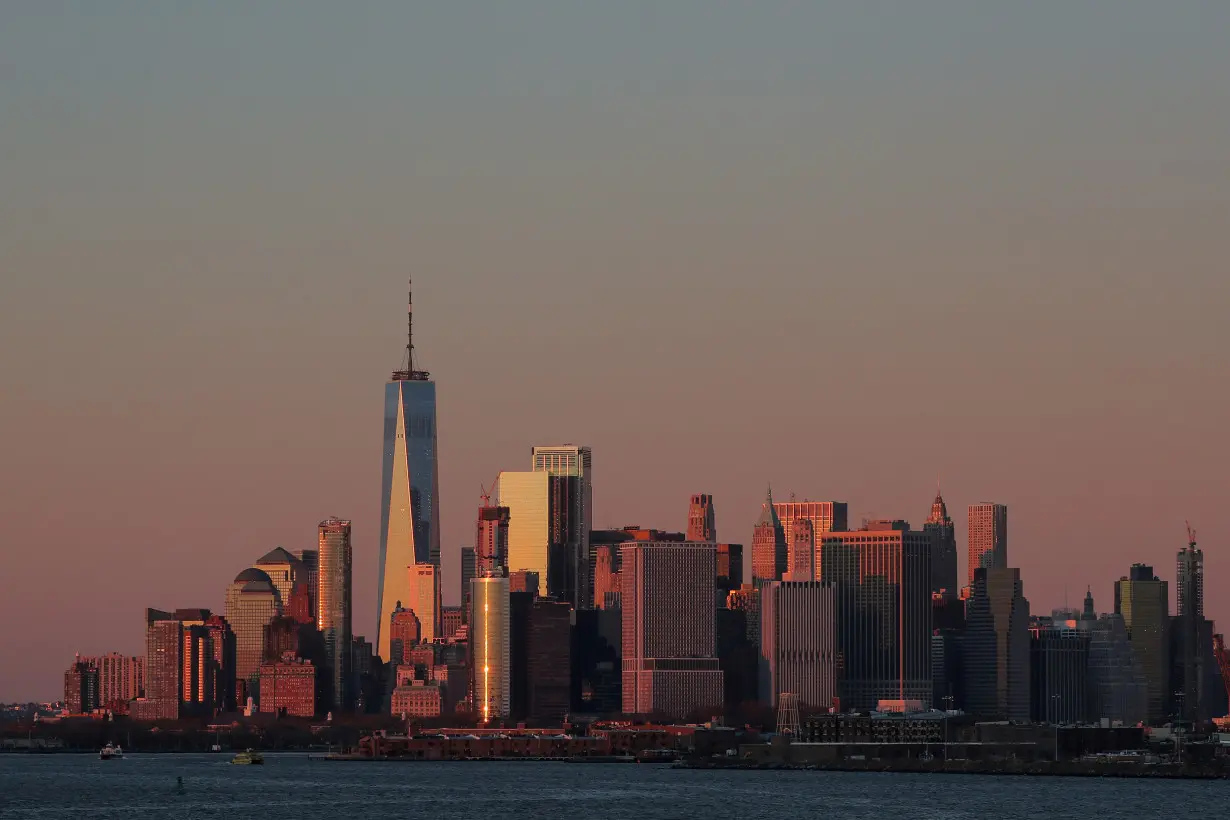 The setting sun is seen reflecting off 1 World Trade Center and other buildings in Manhattan in New York