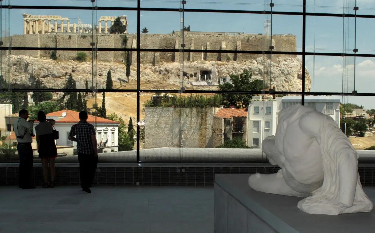 FILE PHOTO: Visitors look at the temple of the Parthenon from inside the new Acropolis museum in Athens