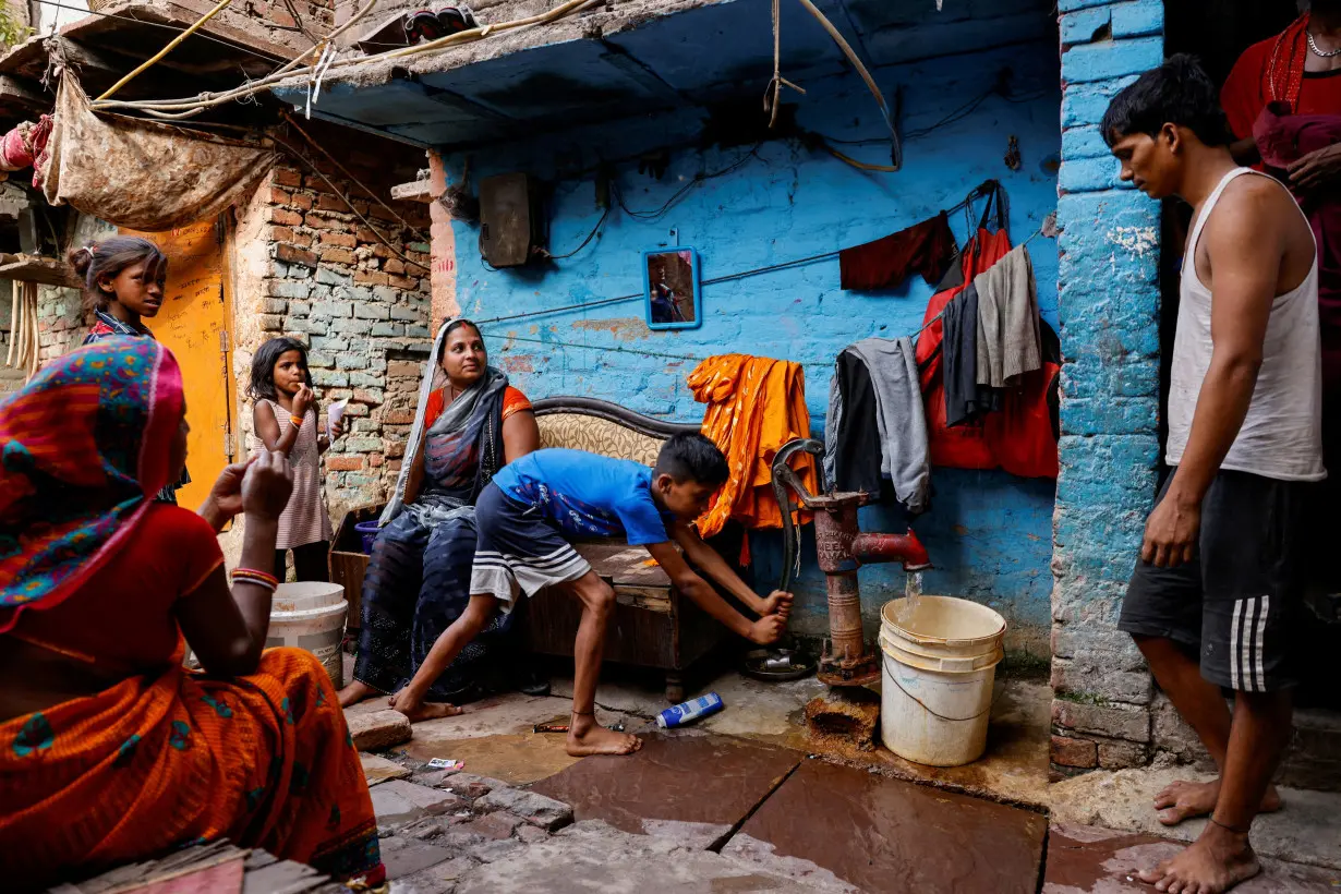 FILE PHOTO: A boy fills water in a container using a hand pump on a hot summer day during a heatwave in New Delhi