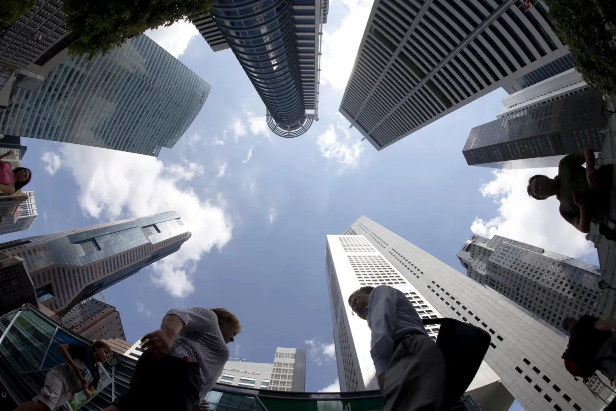 People walk past office buildings at the central business district in Singapore