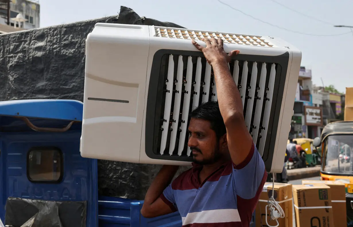 FILE PHOTO: FILE PHOTO: A worker carries an air cooler for delivery to a customer during the heat wave in Ahmedabad