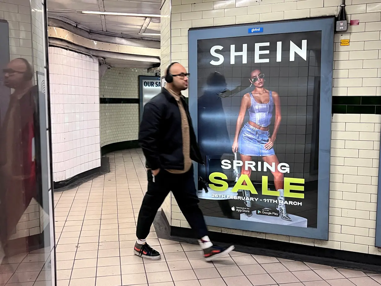 FILE PHOTO: People walk past an advertisement for Shein