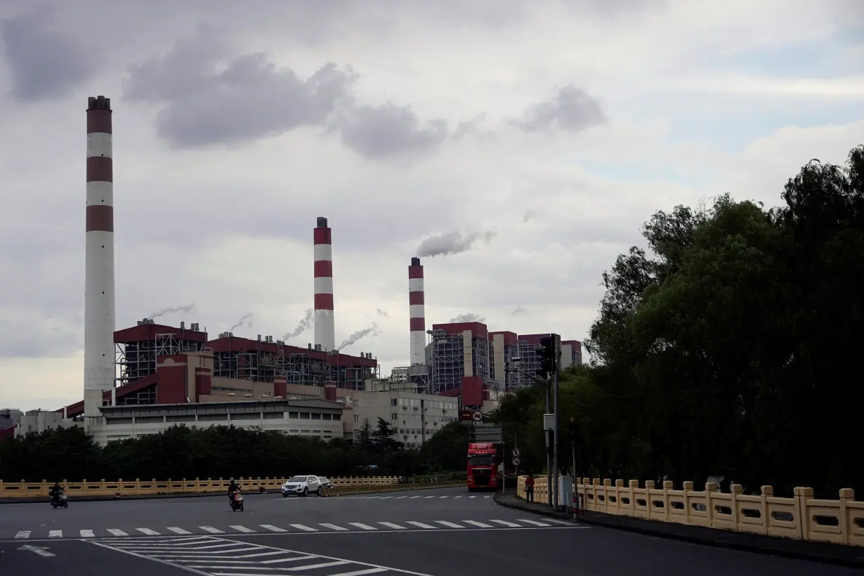 People drive past a coal-fired power plant in Shanghai