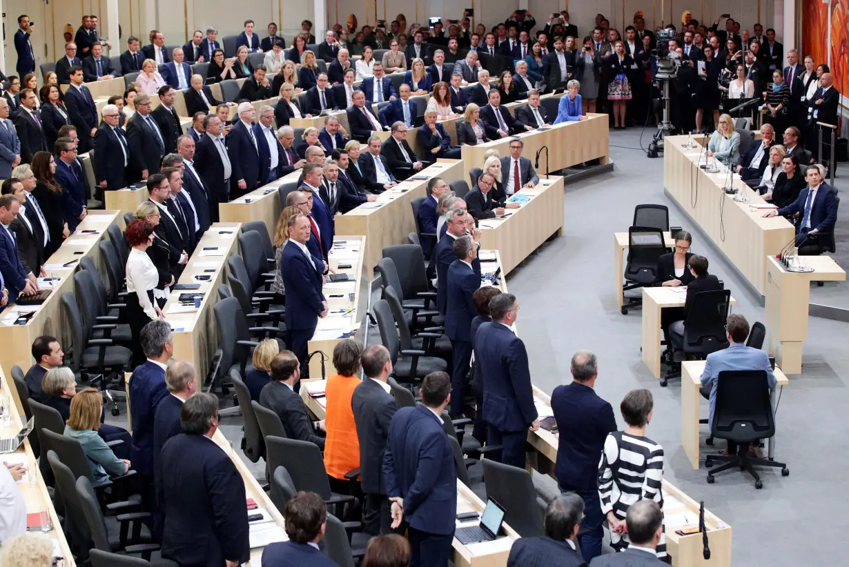 Members of the Parliament stand during a session of the Parliament in Vienna