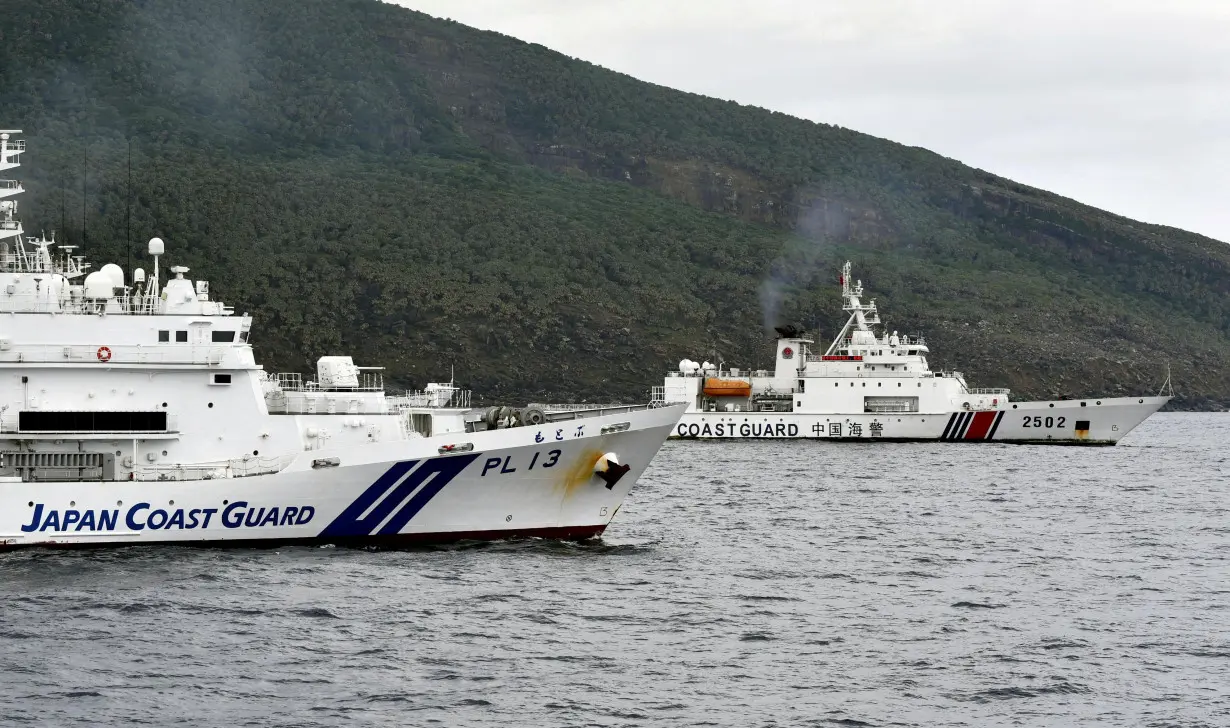 FILE PHOTO: A China Coast Guard vessel sails near a Japan Coast Guard vessel off Senkaku Islands, also called in China as Diaoyu Islands, in the East China Sea