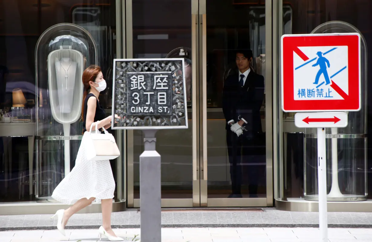 A woman walks past a luxury brand shop at a shopping district in Tokyo