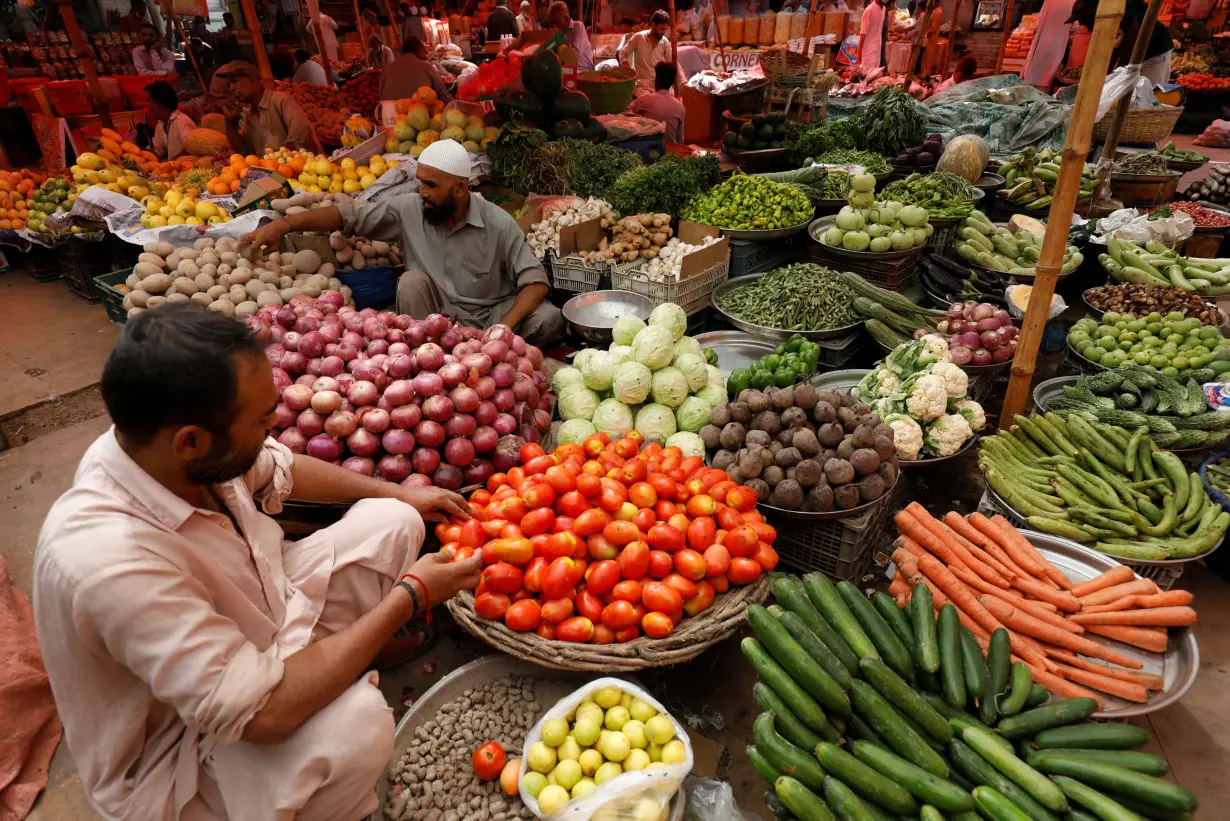 Vendors arrange vegetable baskets while waiting for customers in Karachi