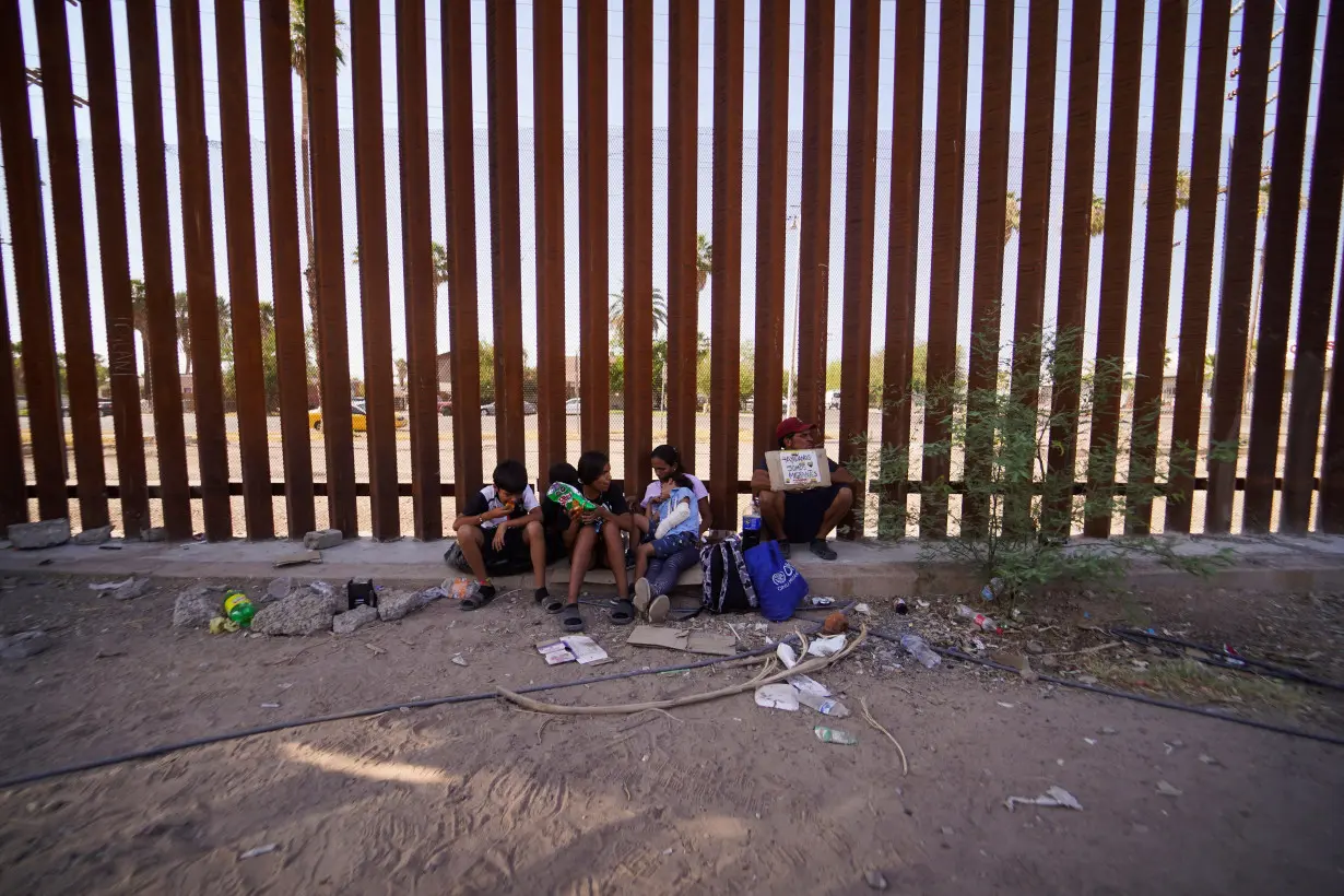 FILE PHOTO: A Colombian family waits next to the border wall during a heat wave in Mexicali