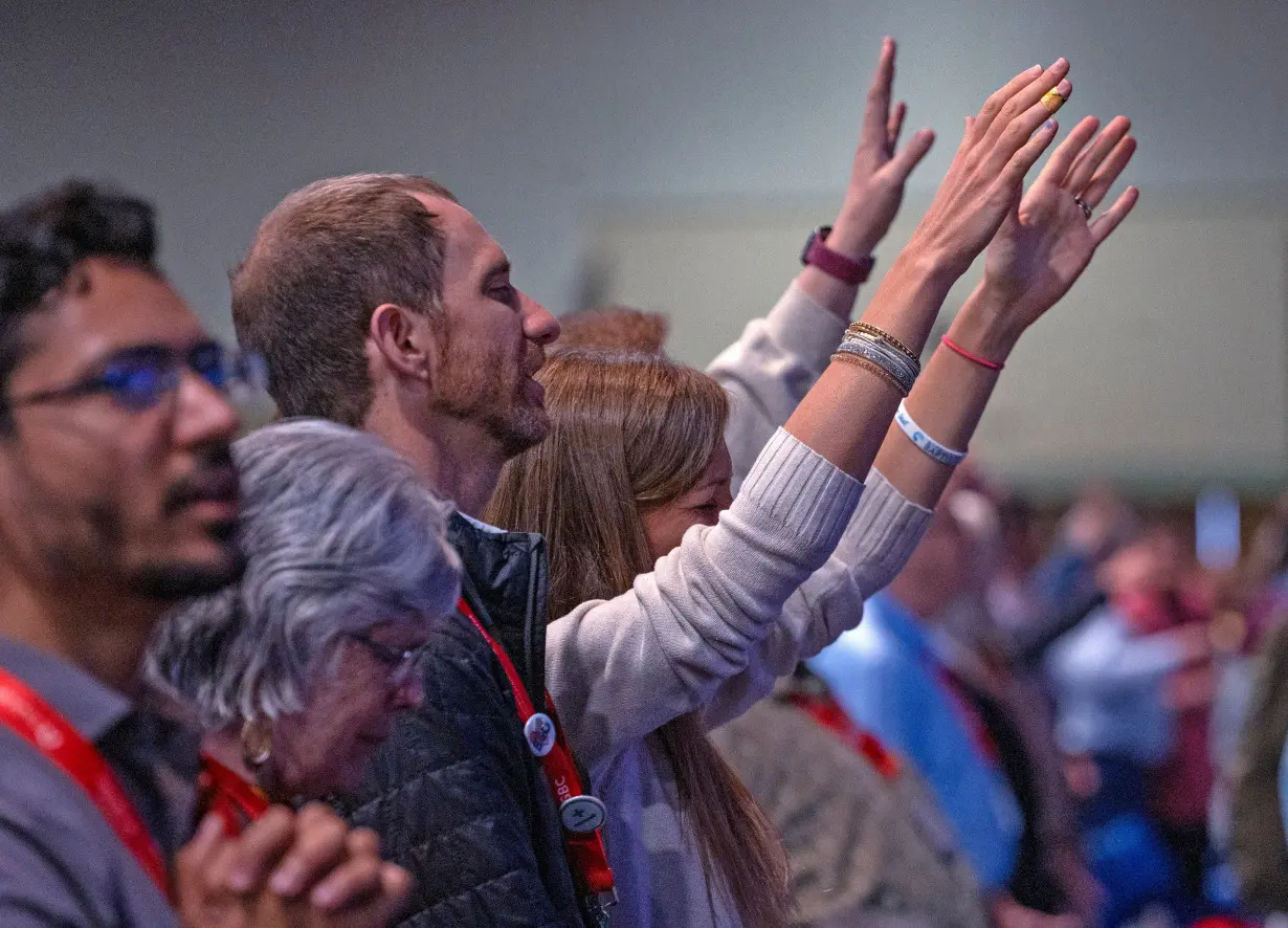 People raise their hands in praise during the Southern Baptist Convention