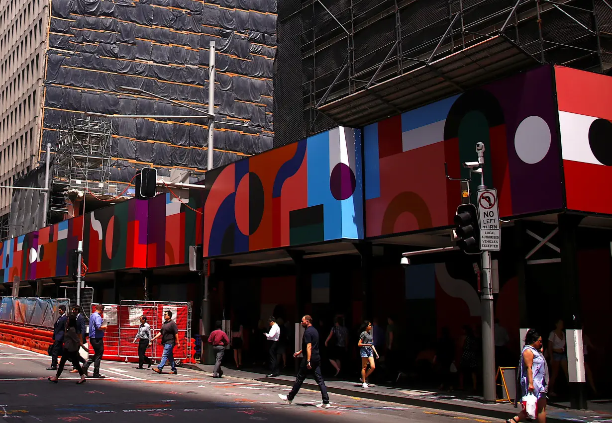 Buildings being renovated and under construction can be seen near shoppers as they walk along a street in the central business district of Sydney