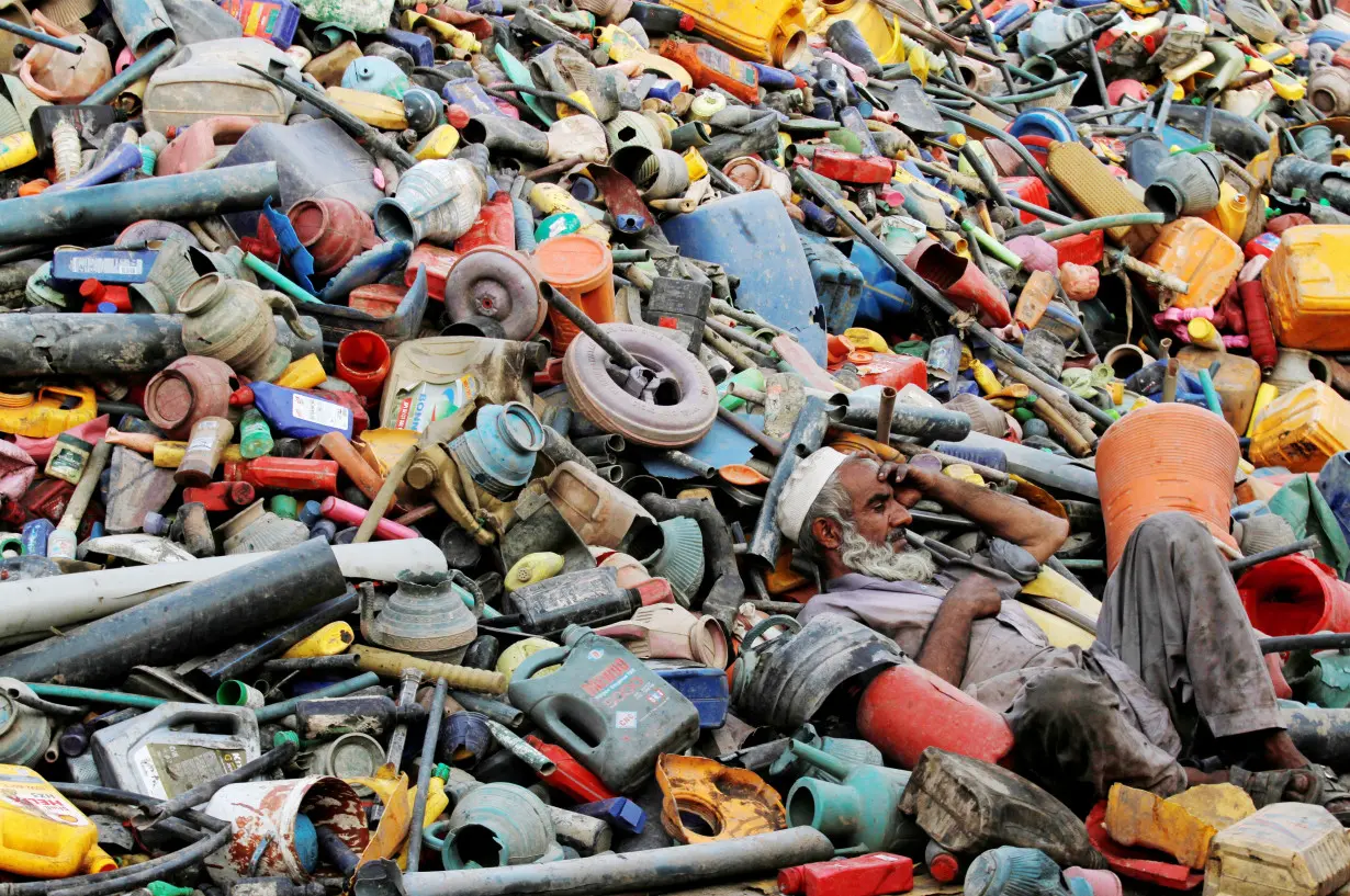 A labourer rests over a pile of recyclables at a yard in Peshawar