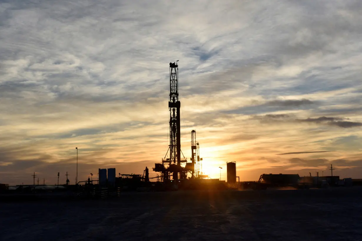 FILE PHOTO: Drilling rigs operate at sunset in Midland