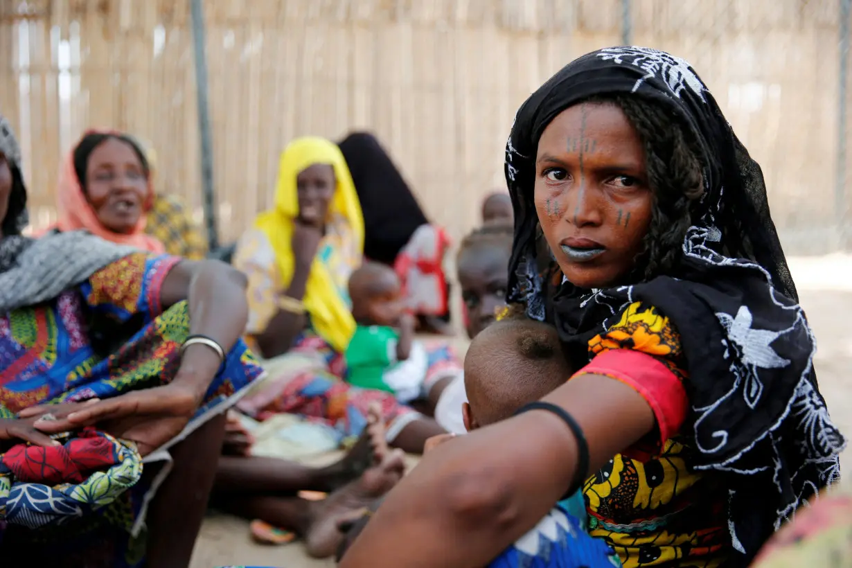 FILE PHOTO: Woman sits outside a shed as she waits for food rations at IDP camp on the outskirts of Maiduguri