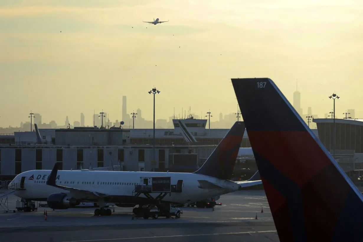 FILE PHOTO: The Manhattan skyline is seen in the background as an airplane takes off at John F. Kennedy International Airport on the July 4th weekend in Queens, New York City