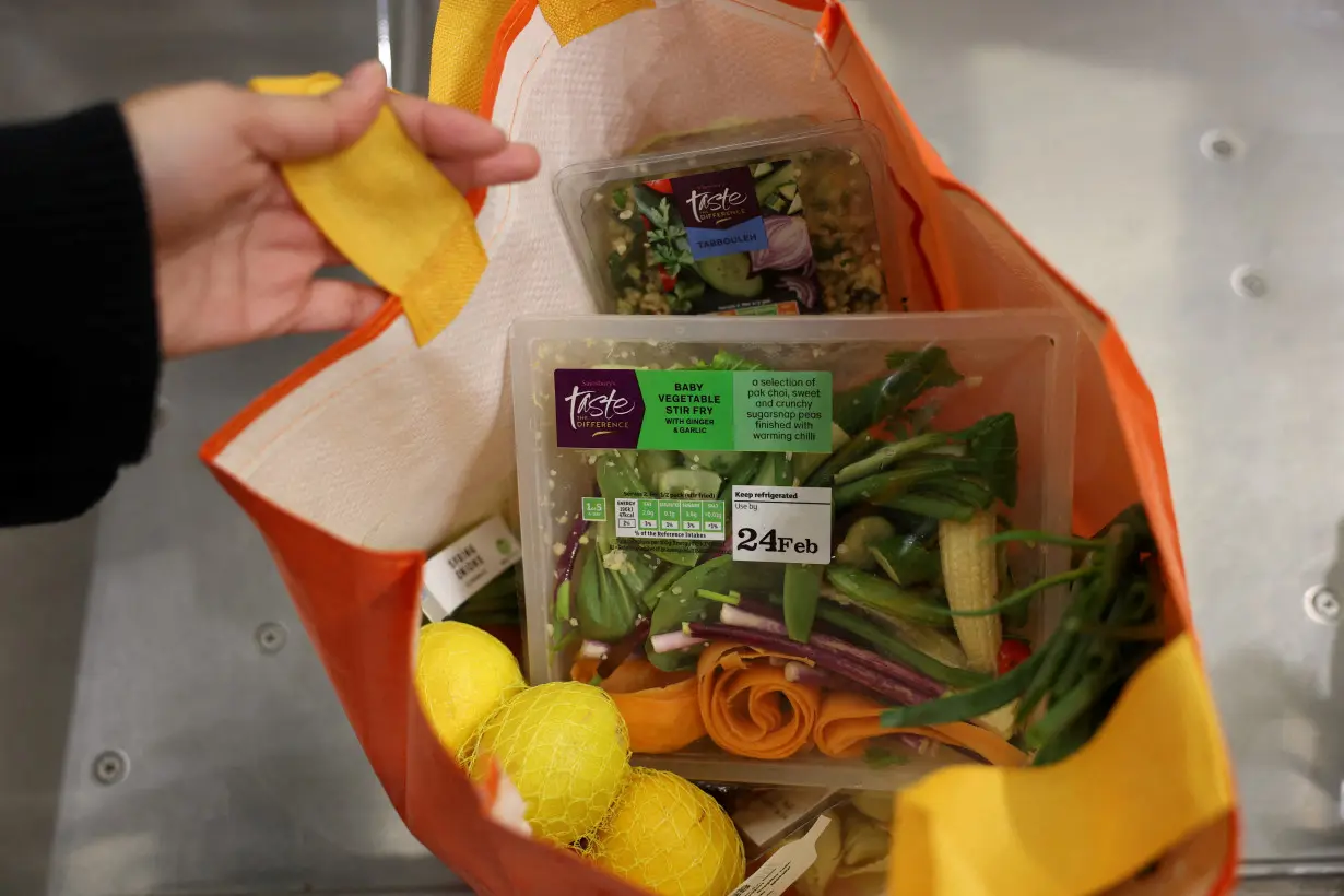 FILE PHOTO: A customer puts groceries inside a reusable bag at the self-checkout inside a Sainsbury’s supermarket in London